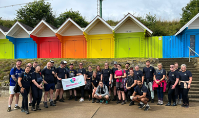Volunteers for Dementia UK stood in front of a row of beach huts